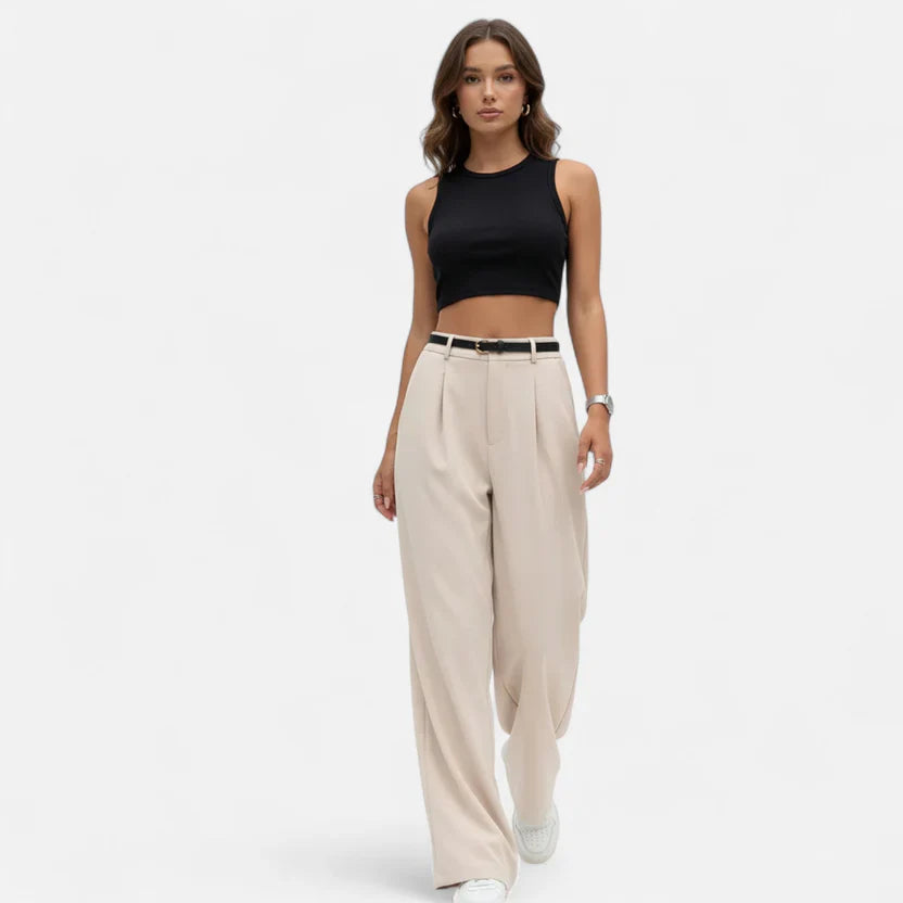 Femme model wearing black crop top and beige wide-leg pants walking confidently.