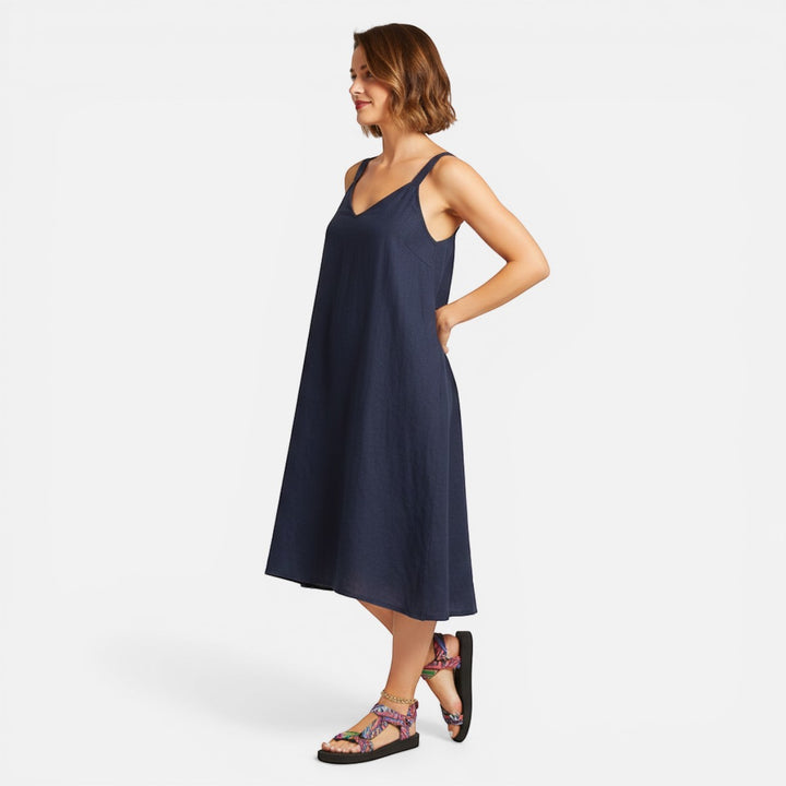 Laurior | Sandales plates pour femmes en fibres naturelles, confortables pour l'été portées avec une robe noire.