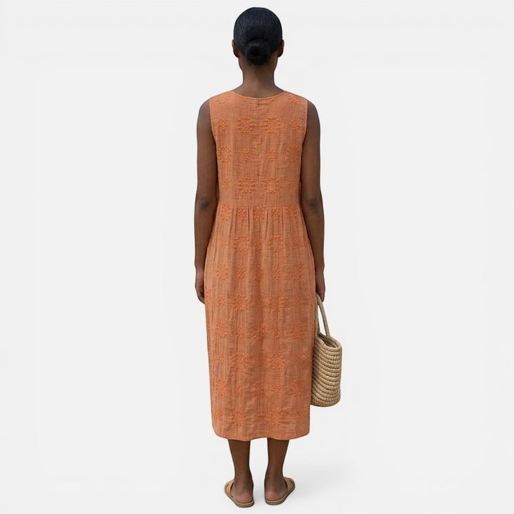 Laurior | Robe sans manches intemporelle taille plissée confort vue arrière portée par une femme avec un sac en osier.