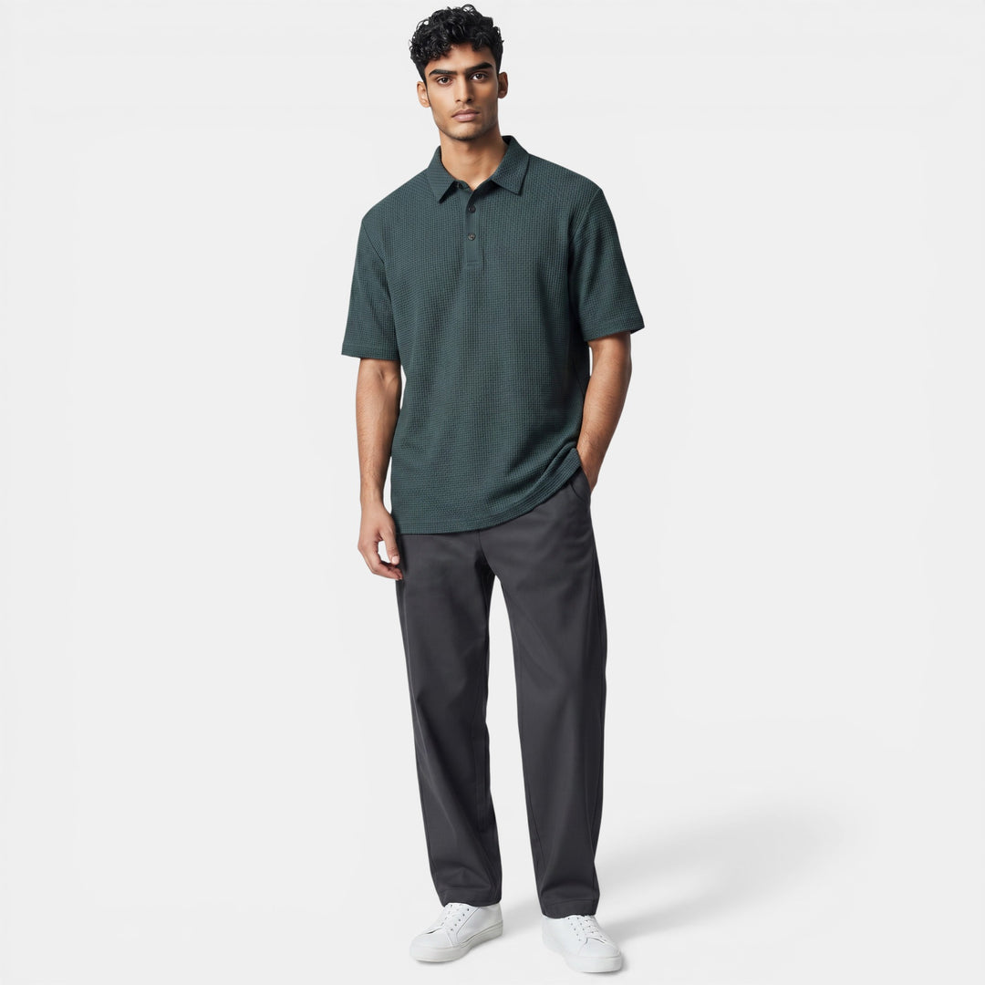 Laurior | Polo de golf homme respirant, élégant et confortable, porté par un homme debout, avec pantalon gris.