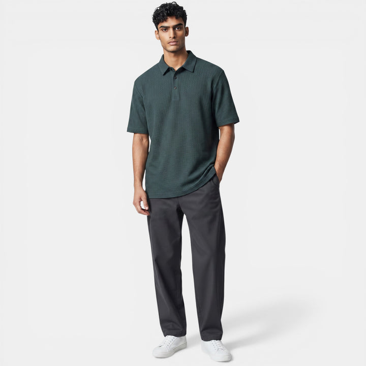Laurior | Polo de golf homme respirant, élégant et confortable, porté par un homme debout, avec pantalon gris.