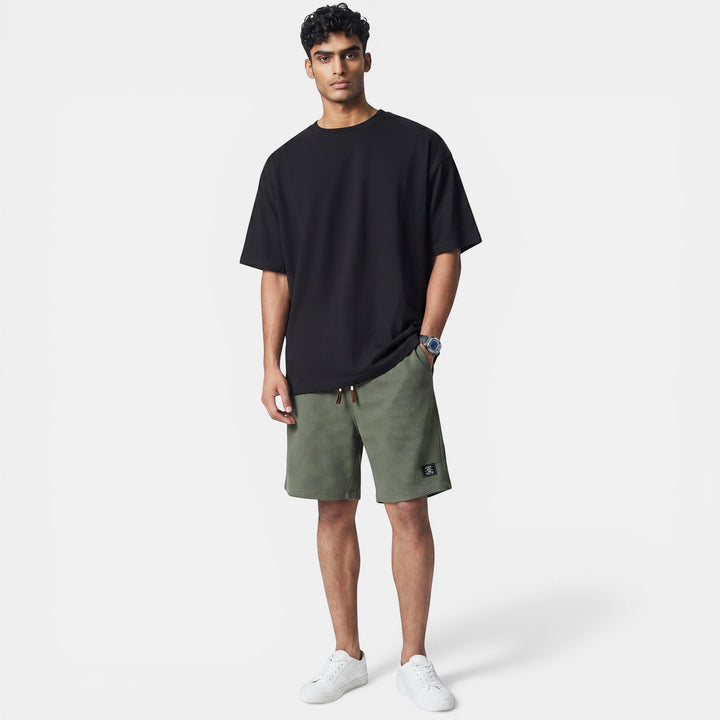 Laurior | Short en Maille Homme Doux Structuré Style Décontracté porté avec tee-shirt noir et baskets blanches.